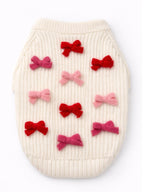 White knitted pet sweater with red and pink bow decorations on a white background