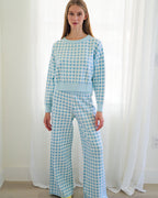 Person standing in a bright room wearing a matching light blue and white gingham two-piece loungewear with yellow socks.