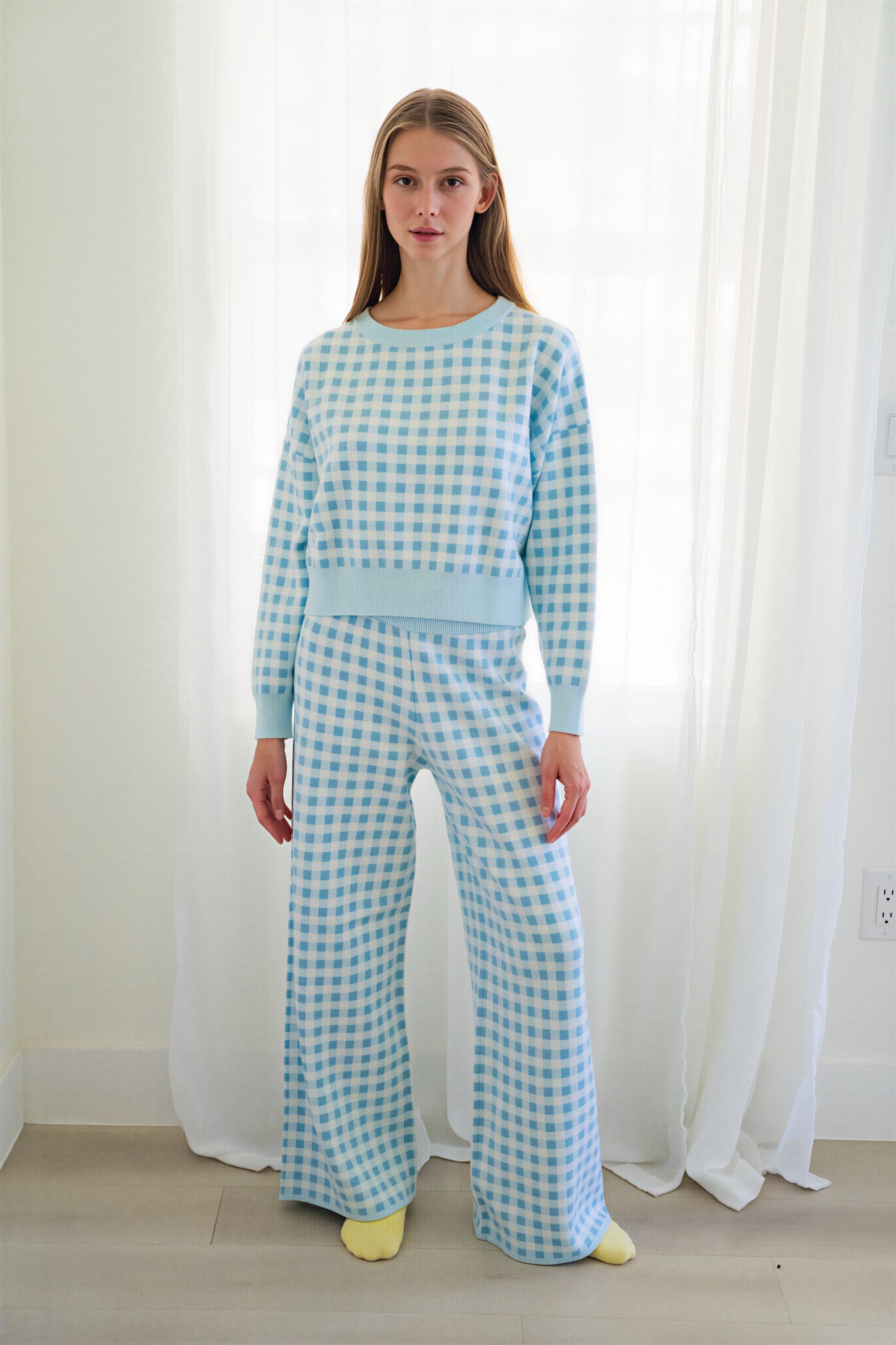 Person wearing a matching light blue and white gingham two-piece loungewear set and yellow socks on a white background.