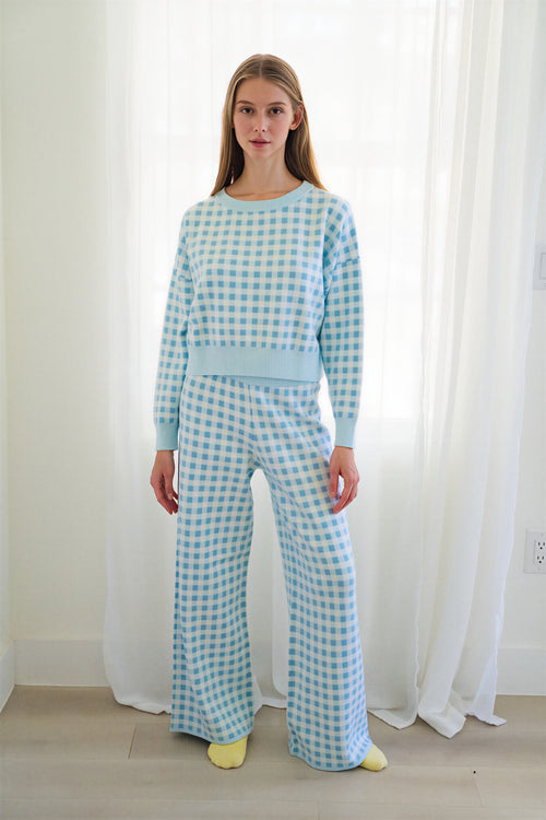 Person wearing a matching light blue and white gingham two-piece loungewear set and yellow socks on a white background.