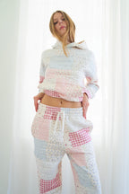 Person modeling a matching patchwork lounge set consisting of a cropped long-sleeve hoodie and drawstring pants in soft pastel colors including pink, blue, and white.
