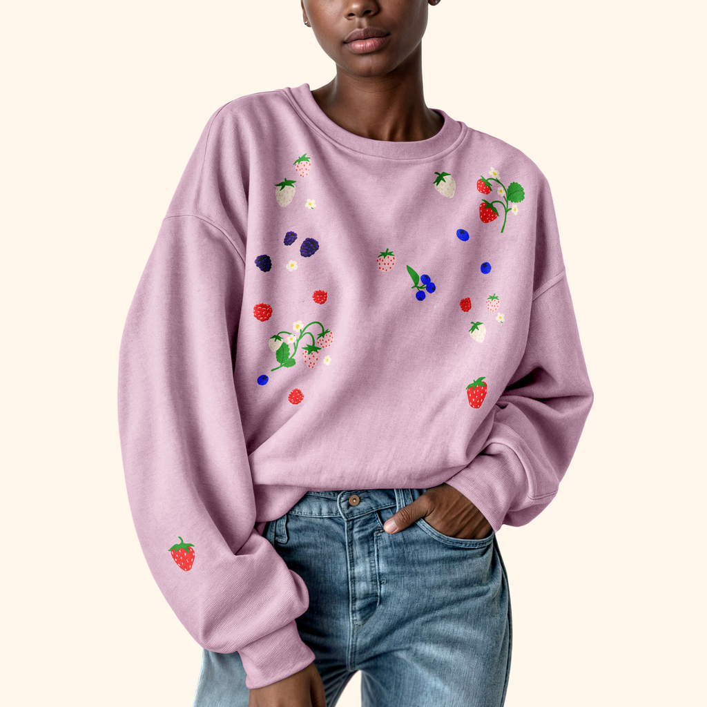 Person wearing a light purple sweatshirt with colorful fruit design srickers on a white background