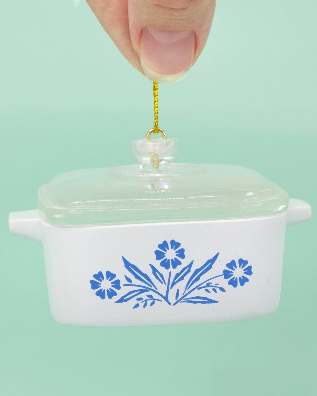 White ceramic ornament with blue floral patterns on a light green background