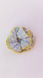 A blue and yellow checkered fabric scrunchie on a white background