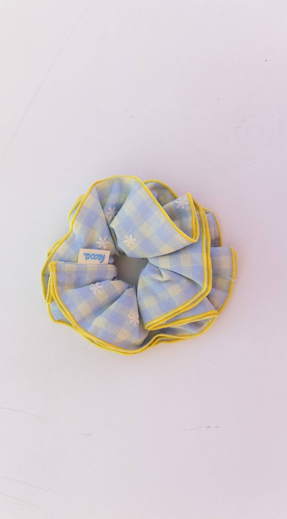 A blue and yellow checkered fabric scrunchie on a white background