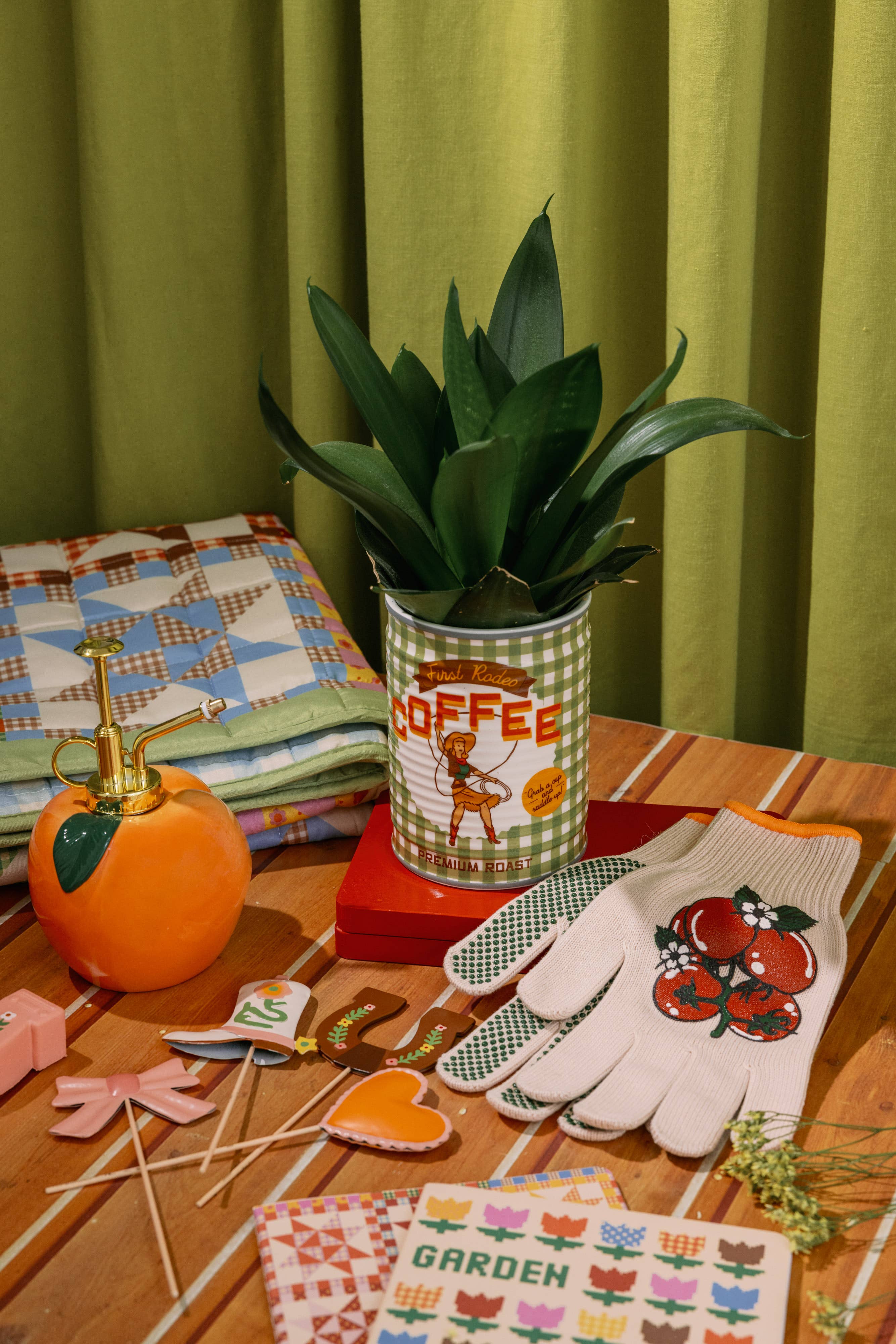 Table with decorative items including a potted plant, pumpkin, and gardening gloves against a green curtain background.