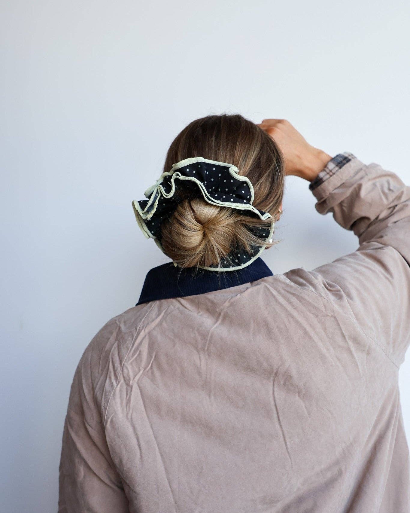 Person wearing a patterned black and white scrunchie with a plain background