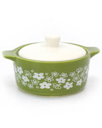 A green ceramic lidded casserole dish inspired trinket box with a white floral pattern on the side and a white lid, shown on a white background.