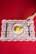 Dessert plate with slice of cake on a frosting patterned place mat against a red background