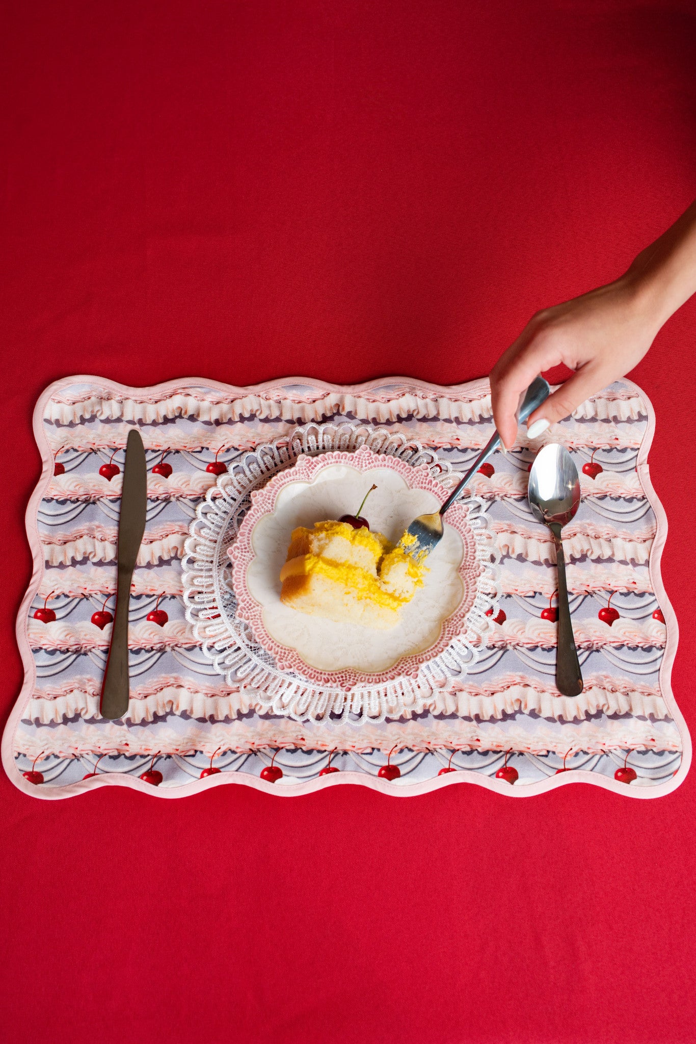 Dessert plate with slice of cake on a frosting patterned place mat against a red background