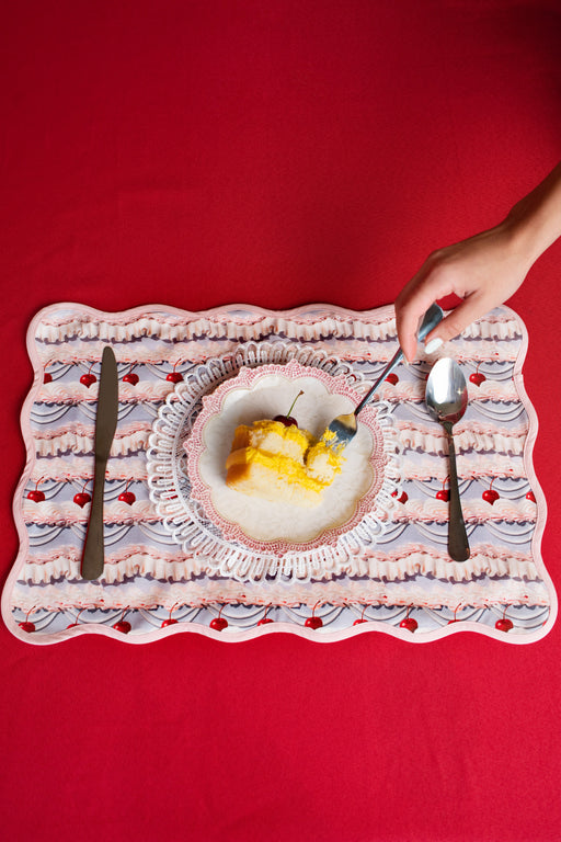 Dessert plate with slice of cake on a frosting patterned place mat against a red background