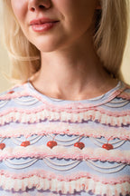 Close-up of a person wearing a pink and purple frosting patterned shirt with cherries on it