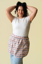 Person in a white shirt and blue jeans wearing a pink and purple frosting pattern on a beige background.