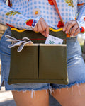 Person holding a green bag with a card labeled 'SAGE' in an outdoor setting