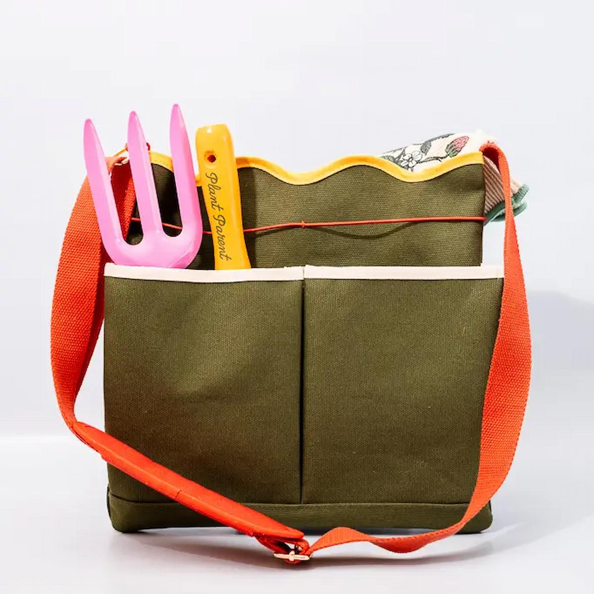 Green tote bag with red strap and gardening tools on a white background