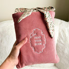 Pink book sleeve with floral ribbon and 'Let's Read Your Book' text on a white surface.