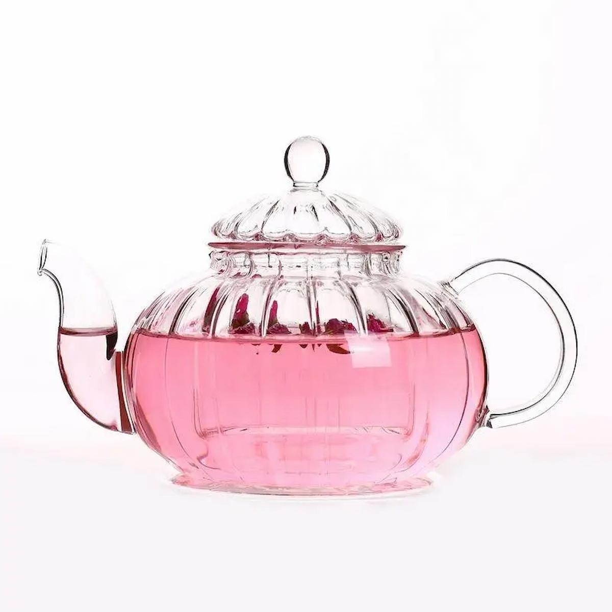 Glass teapot with pink liquid on a white background