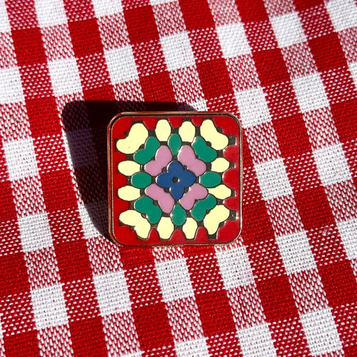 Colorful square brooch on a red and white checkered fabric background