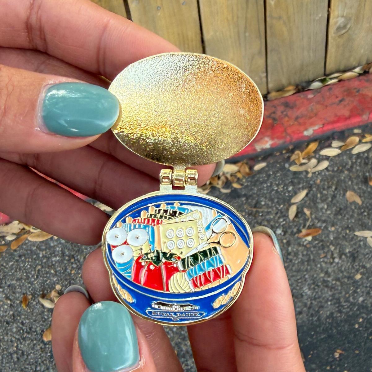 Colorful pocket watch held by a hand with teal nail polish on a street background