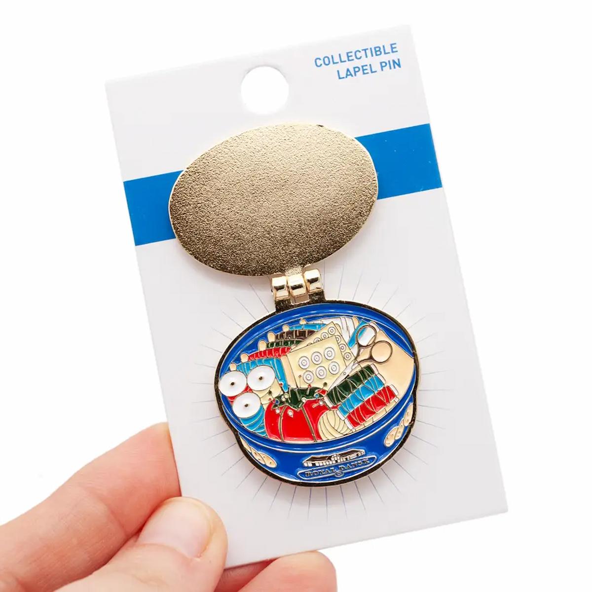 Collectible lapel pin on a card held by a hand