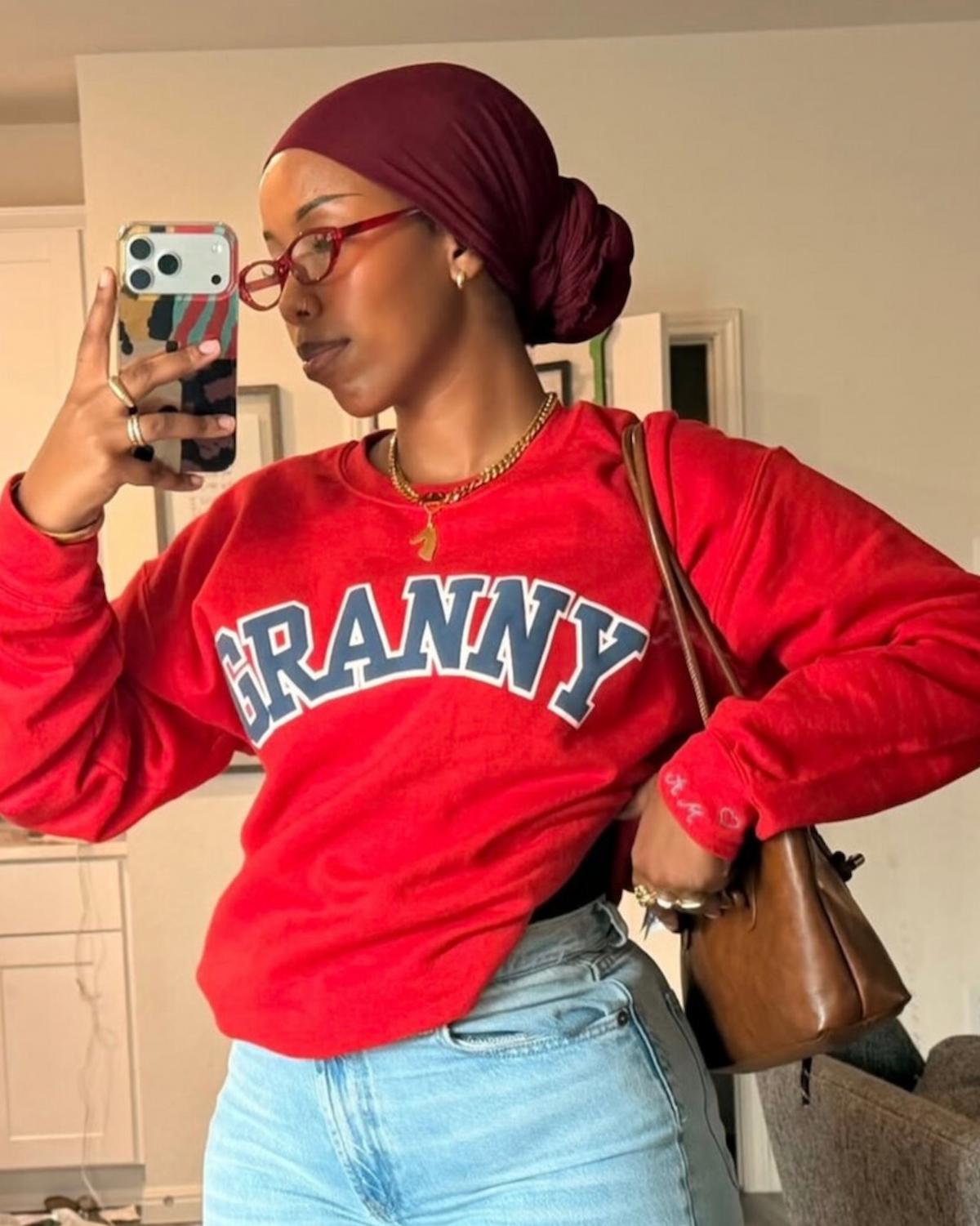 Person wearing a red sweatshirt with 'GRANNY' text, taking a mirror selfie.