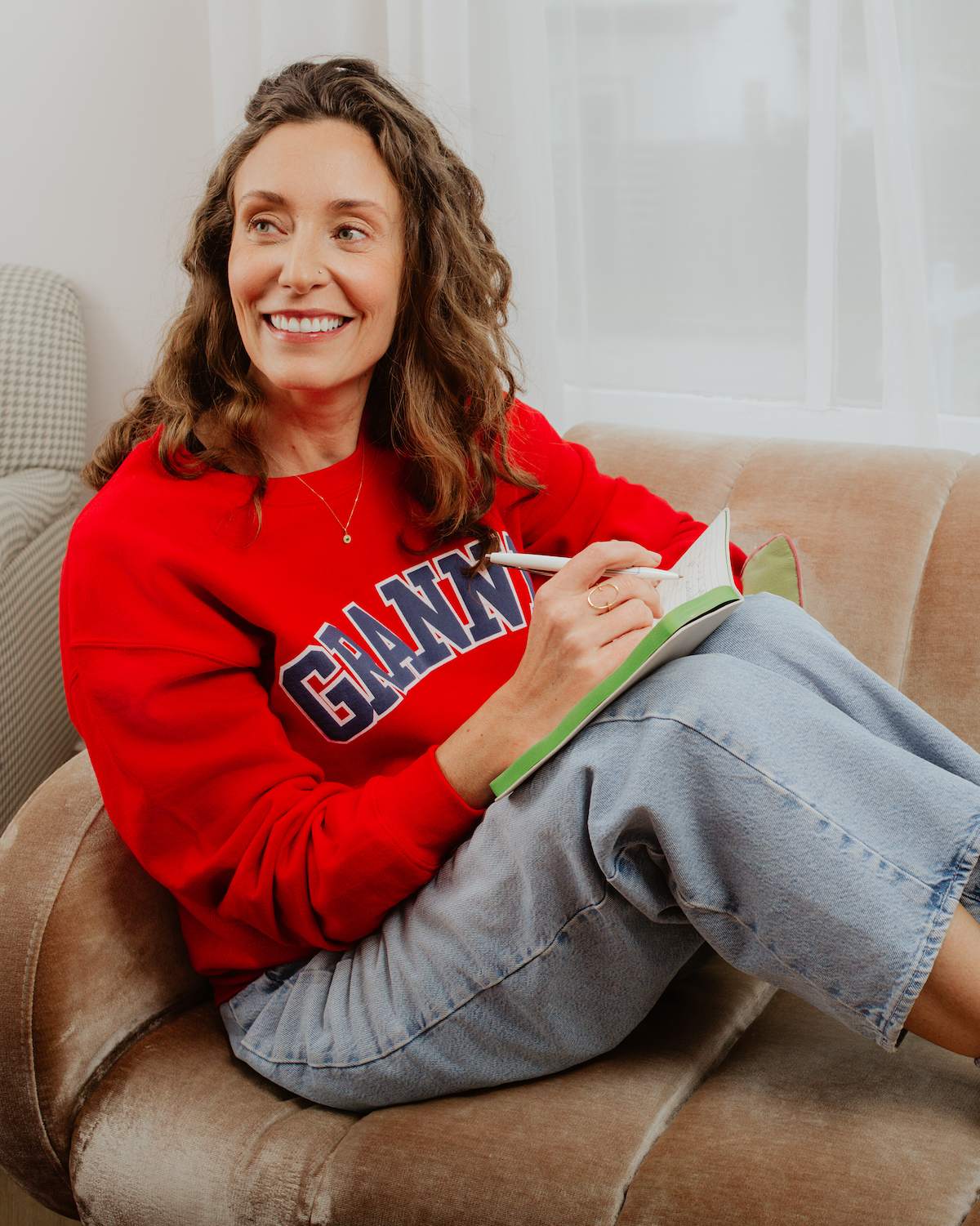 Woman in a red sweatshirt with 'Granny' on it, sitting on a couch and writing in a notebook.