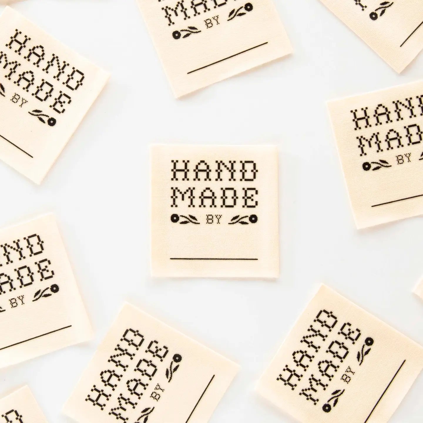 Multiple 'Hand Made by' labels scattered on a light background