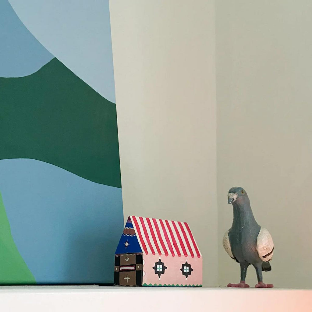 Small model houses and a bird figurine against a colorful abstract background