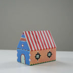 Colorful paper house model with a red and white striped roof on a gray background