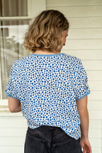 back view on model of blueberry print tee standing in front of a white house