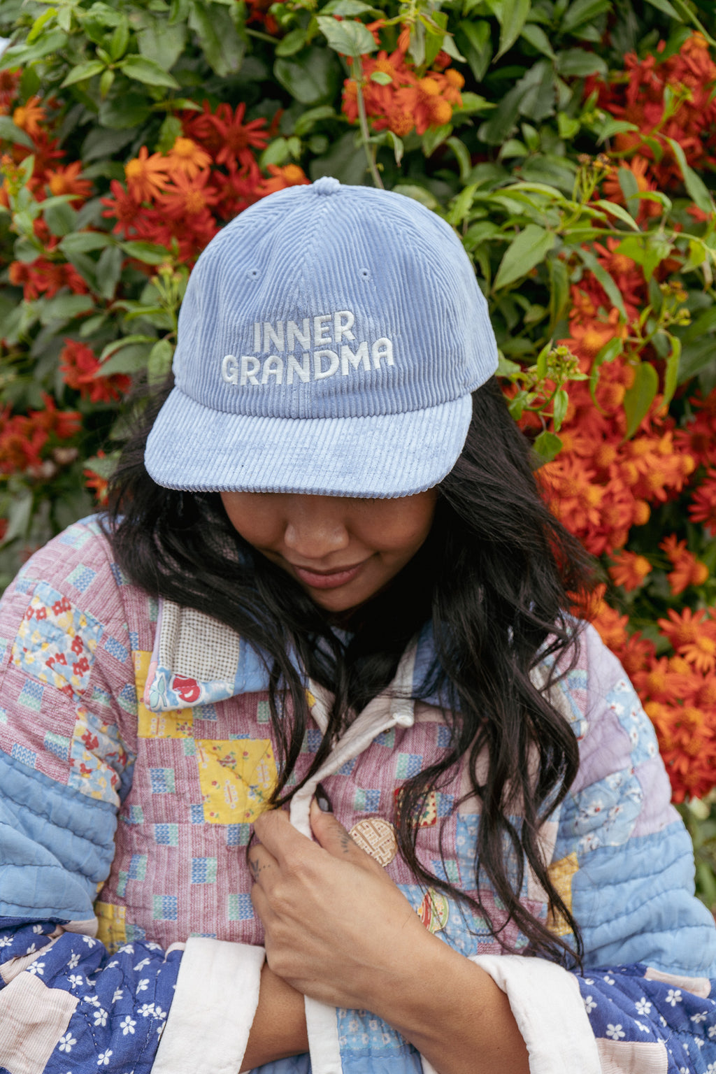Blue corduroy hat with inner grandma written  across on a women against a floral background. 