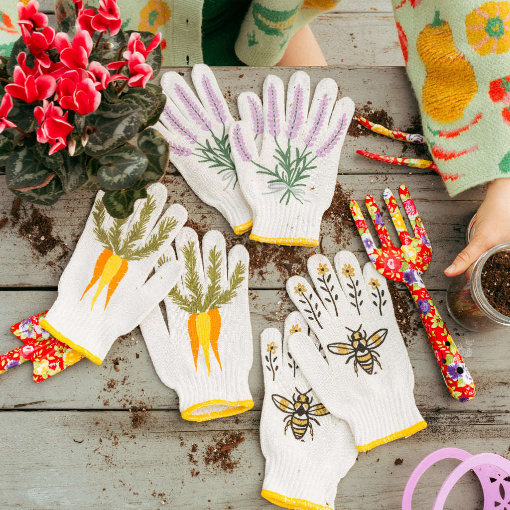 Gardening gloves with plant designs on a wooden surface with gardening tools and plants.