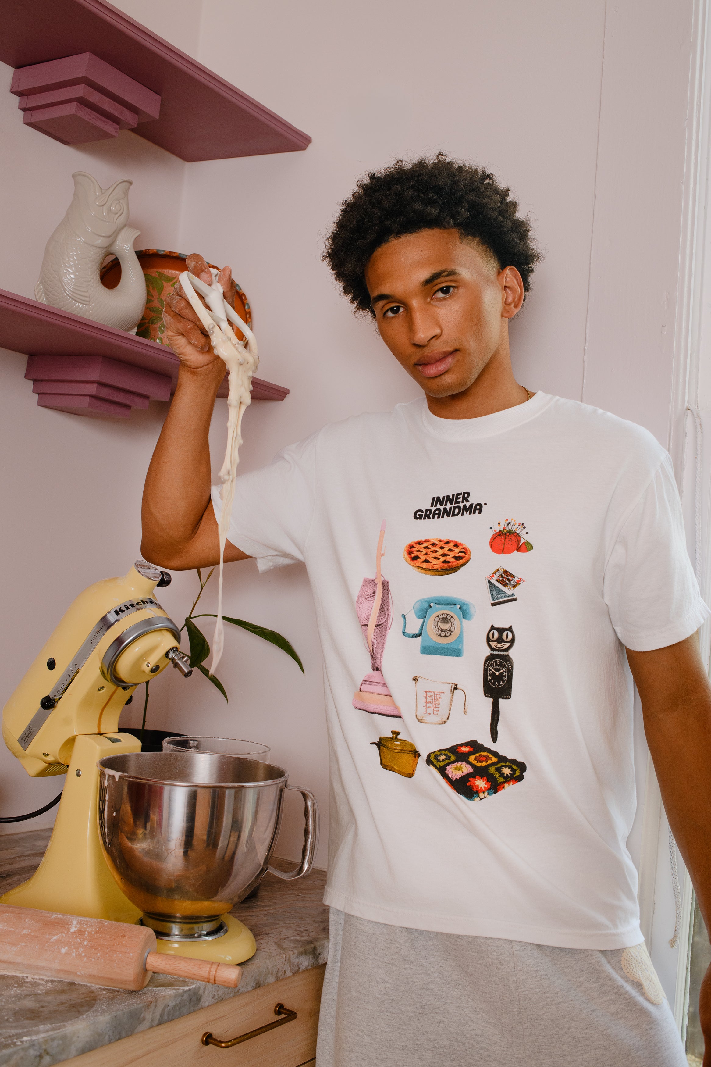 Person wearing a white t-shirt with retro graphic designs in a kitchen setting