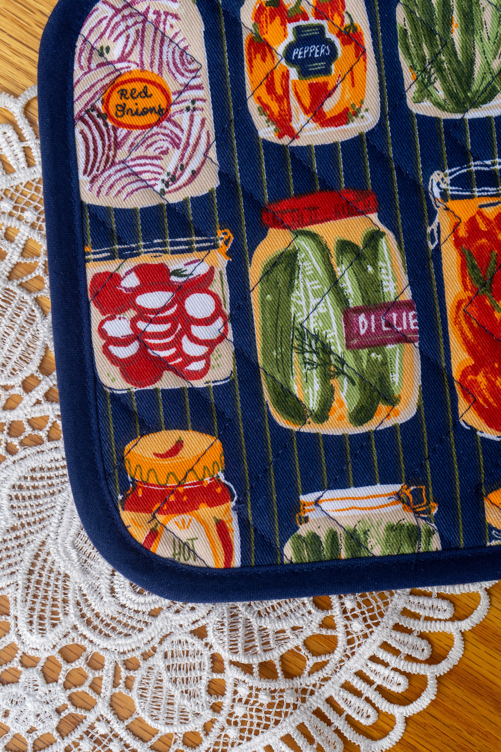 Close up Potholder with jarred vegetables design on a wood table