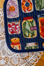 Close up Potholder with jarred vegetables design on a wood table