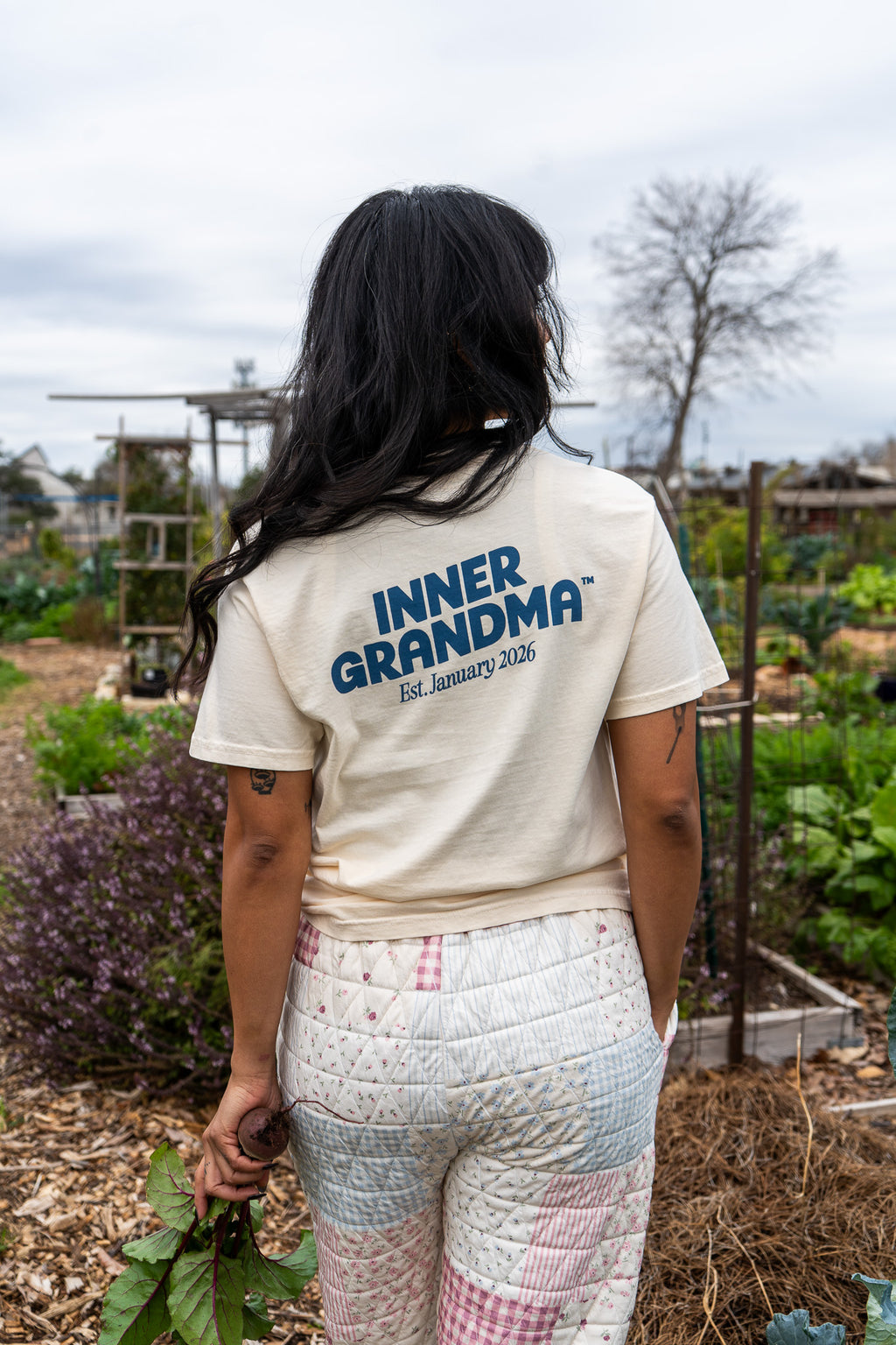 Person wearing a 'INNER GRANDMA' t-shirt in an outdoor garden setting