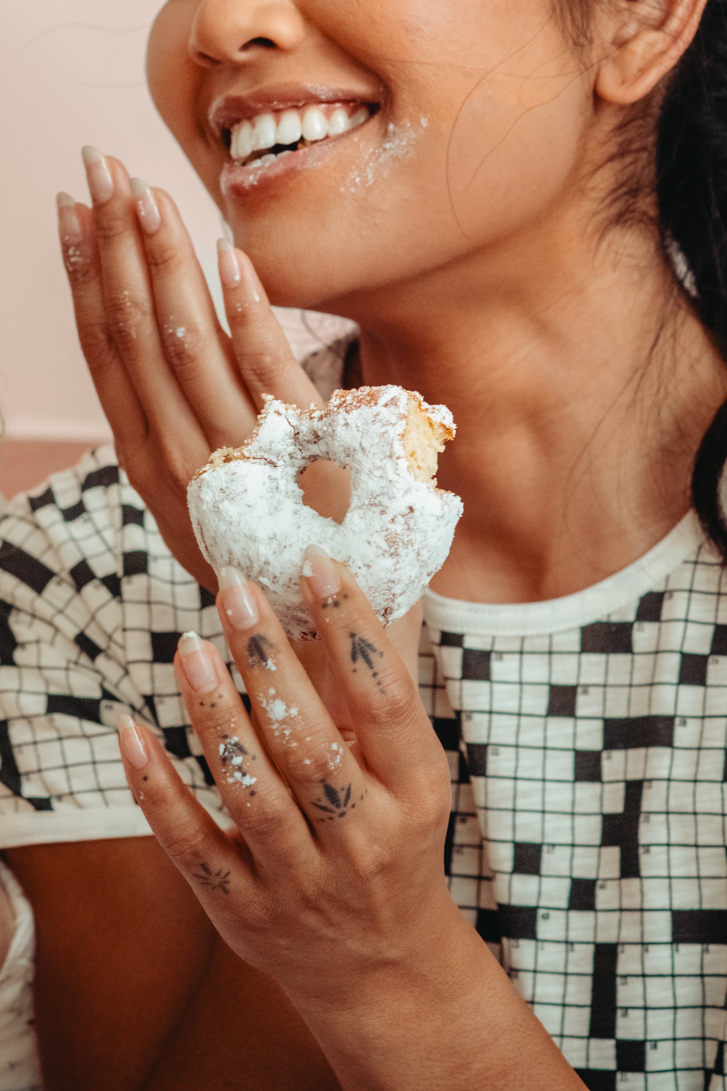 Woman holding a textured donut wearing the crossword puzzle tee 