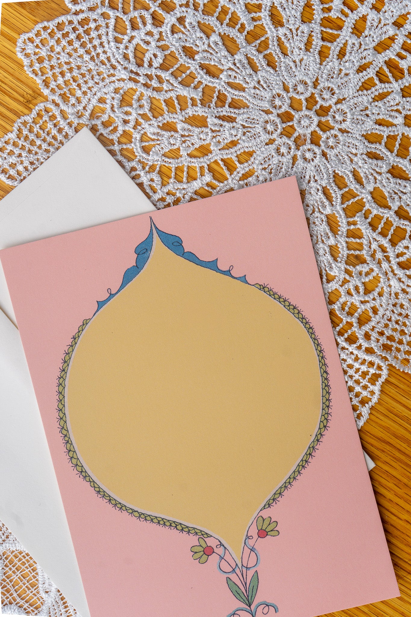 Pink and Yellow Oval card on a set of doily on a wood table