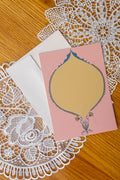 Pink and Yellow Oval card on a set of doily on a wood table