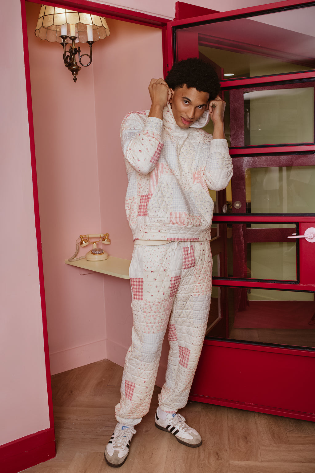 Person wearing a matching outfit in a room with pink walls and a red wardrobe.