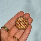 Small pie-shaped decorative item held in a hand against a light blue background