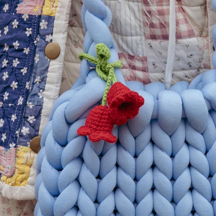 Blue braided fabric with a red knitted flower on a quilted background