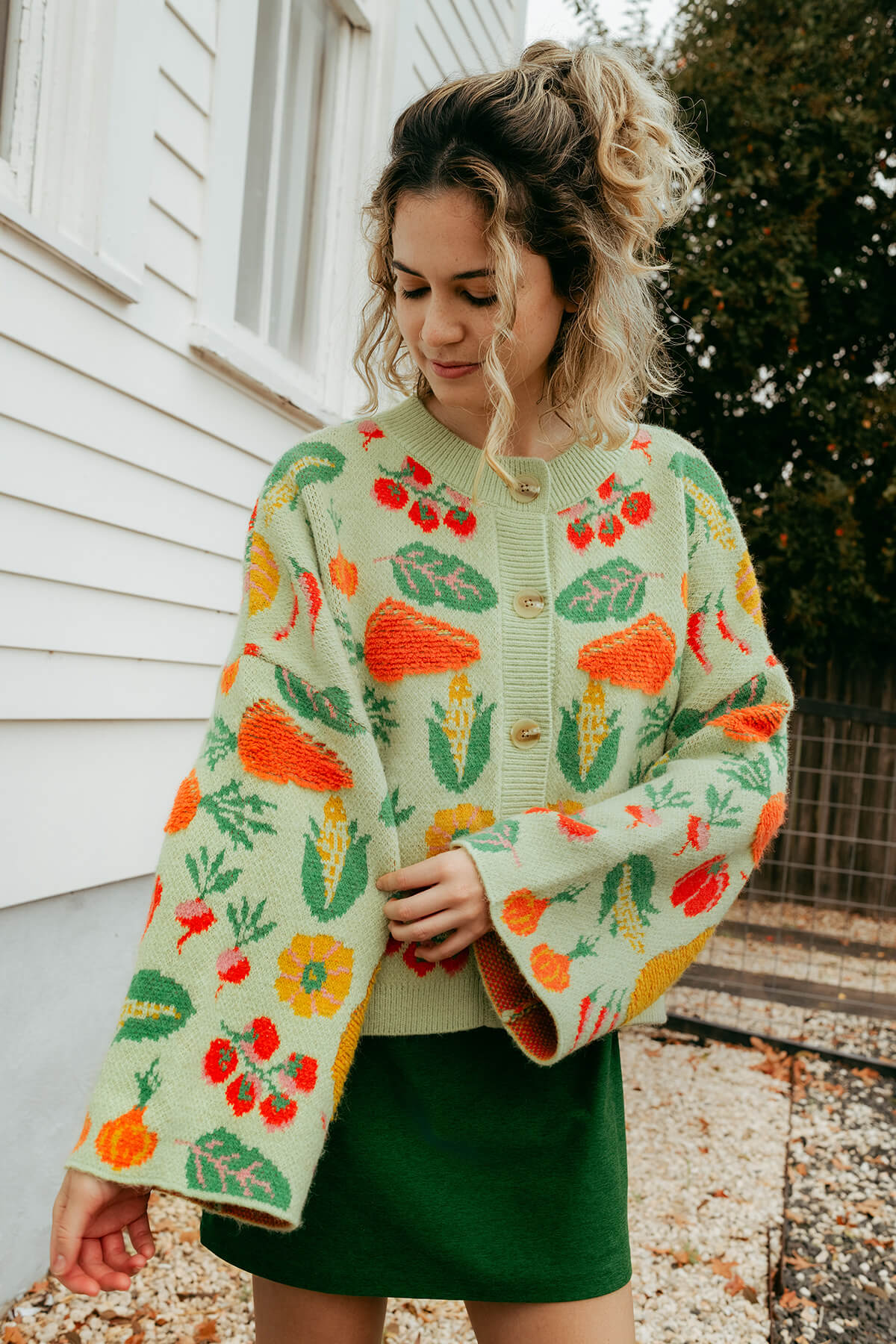 Woman wearing a veggie garden patterned sweater outdoors