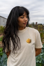 Person wearing a beige t-shirt with sourdough bread  in an outdoor setting