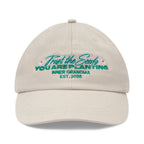 Beige cap with embroidered text and floral designs on a white background