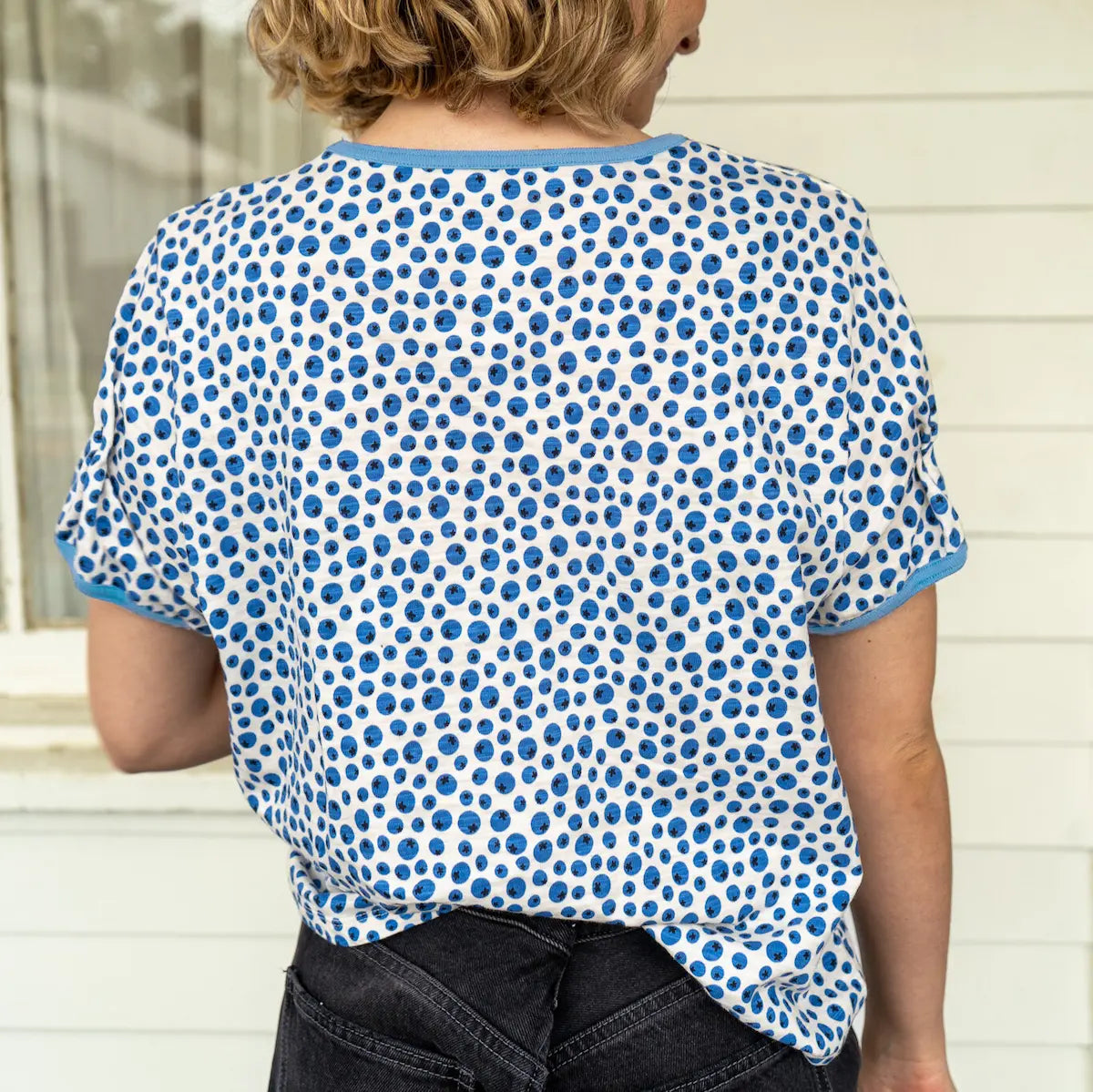 Person wearing a blue and white blueberry patterned shirt with a neutral background