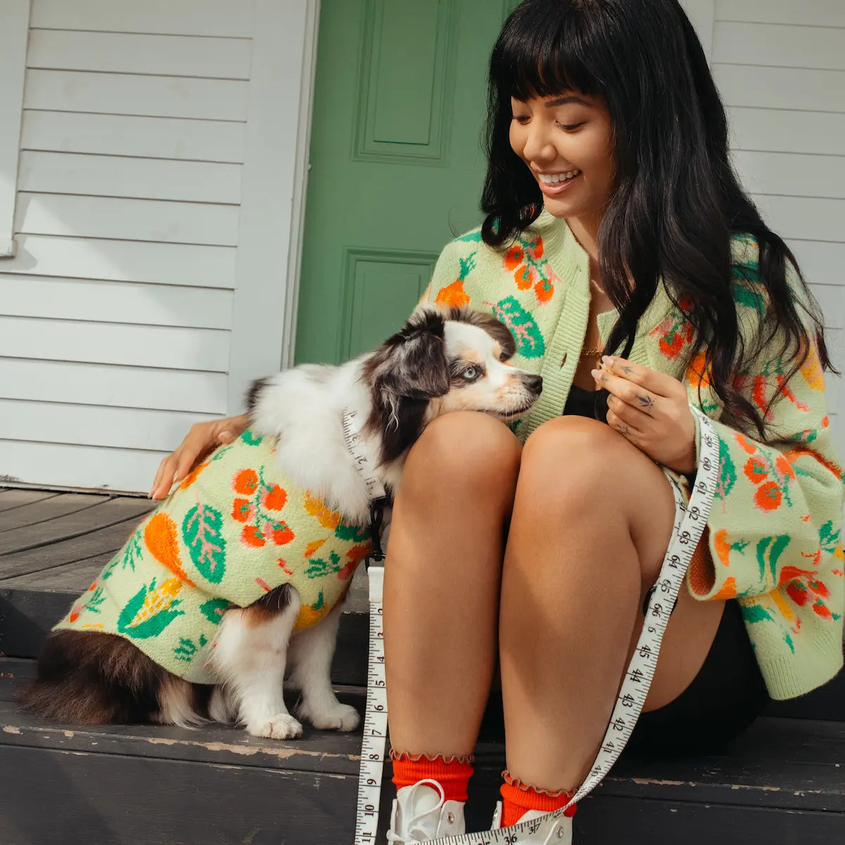 Woman and dog wearing matching veggie outfits sitting on a step.