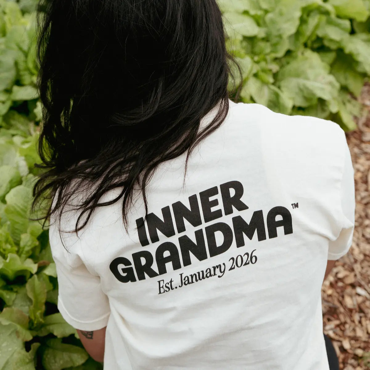 Person wearing a white shirt with 'INNER GRANDMA Est. January 2026' text in a garden setting