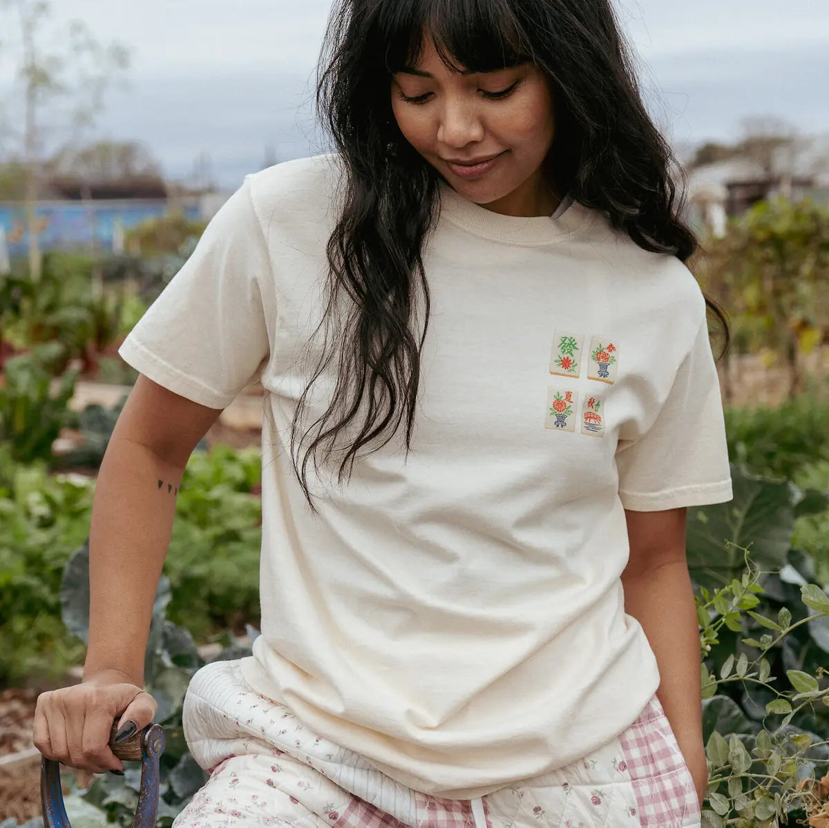 Woman wearing a cream t-shirt with a mahjong tile design outdoors
