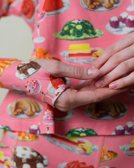 Shot of thumbhole and sleeve detail of a pink patterned long sleeve shirt.